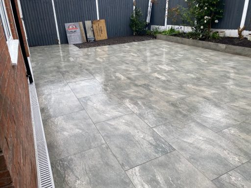Patio area with grey tiled flooring and minimal landscaping.
