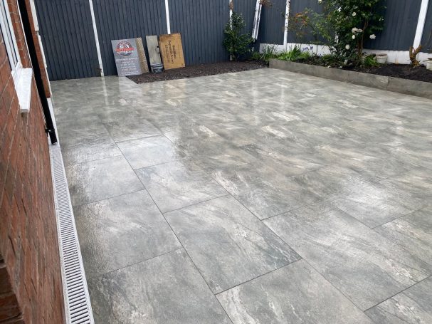 Natural Stone Newly laid grey tiled patio with potted plants and a clean, polished surface.