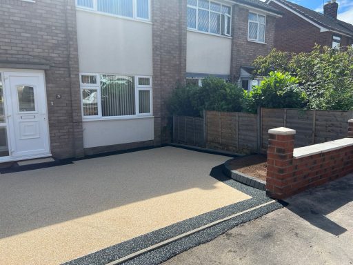 Paved outdoor area in a residential setting, featuring a path and garden shrubs.