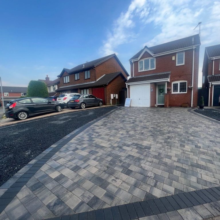 Newly laid patterned red concrete driveway in front of a red-brick house.