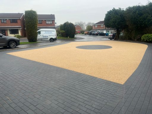 A large, circular gravel area on a brick drive in a residential setting.
