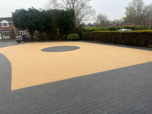 A driveway featuring a circular gravel area surrounded by dark paving.