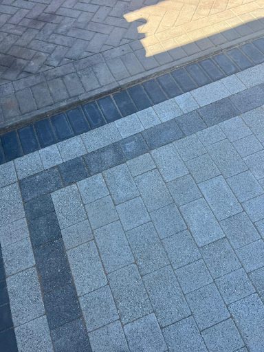 Paved surface with a geometric pattern in grey and blue tones.