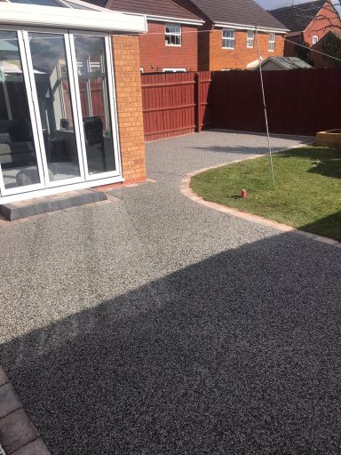 Paved garden area with a conservatory, grass, and bordered pathways.