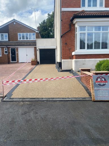 A driveway with a barrier and warning signs in front of a residential house.