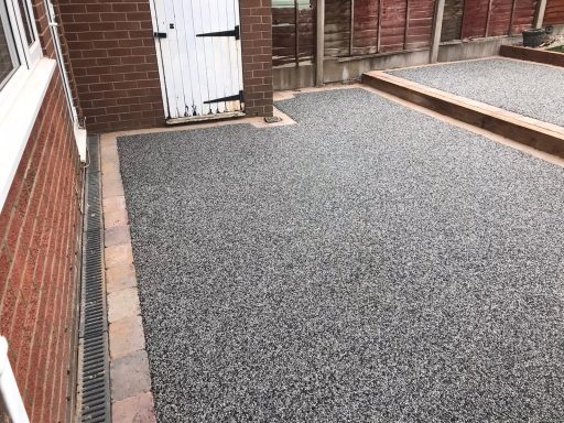 A gravelled area with a brick border and a white door in the background.