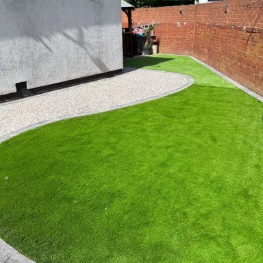 Lush green lawn with a curved gravel border in a garden setting.