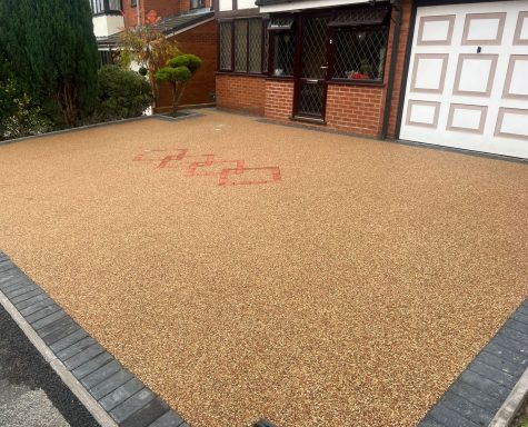 Gravel driveway with red markings and a brick border in front of a house.