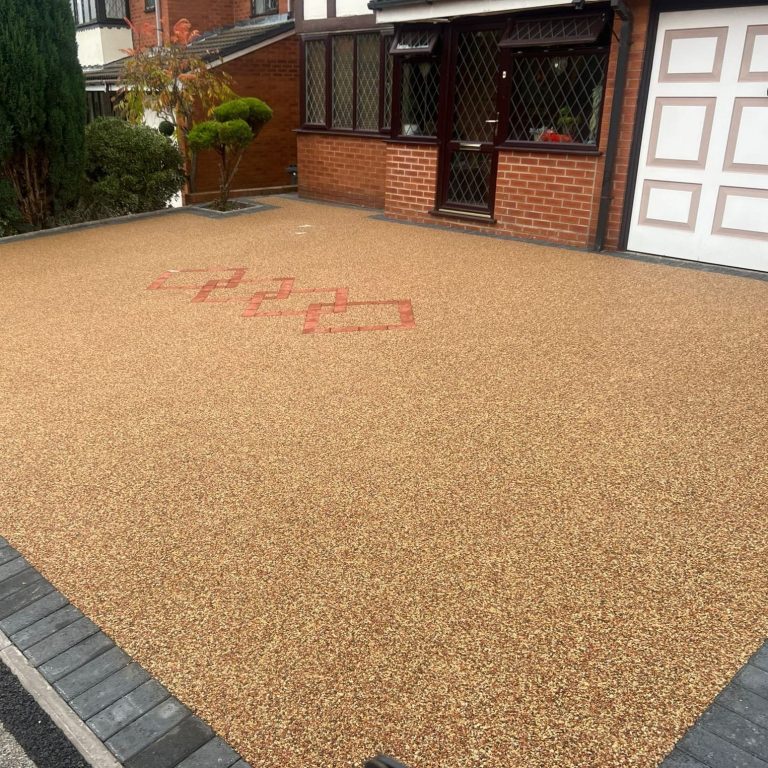 A gravel driveway with red markings and a house with a garage door in the background.