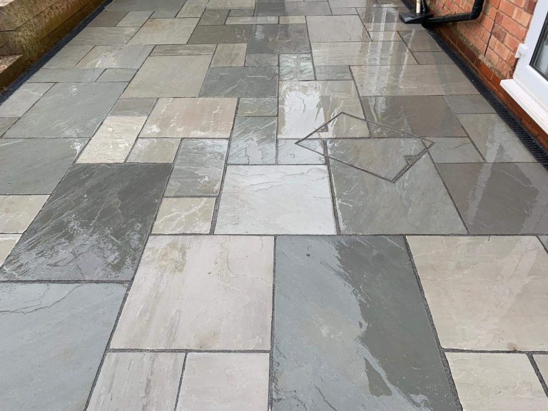 Wet stone patio composed of large, rectangular tiles in varying shades of grey.