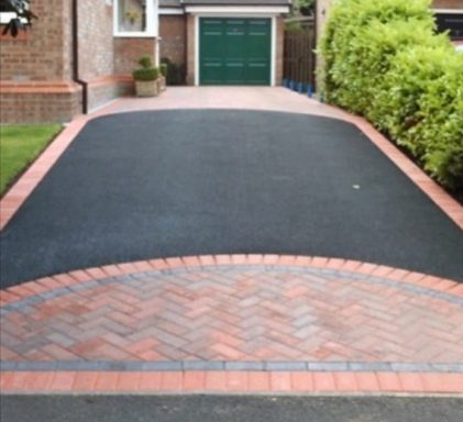 Tarmac drive with brick border and curved entrance leading to a green garage door.