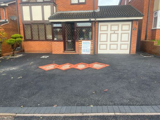 A brick house with a driveway displaying four orange diamond shapes.