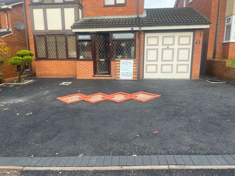 Front view of a house with a driveway featuring orange diamond pattern and a garage.