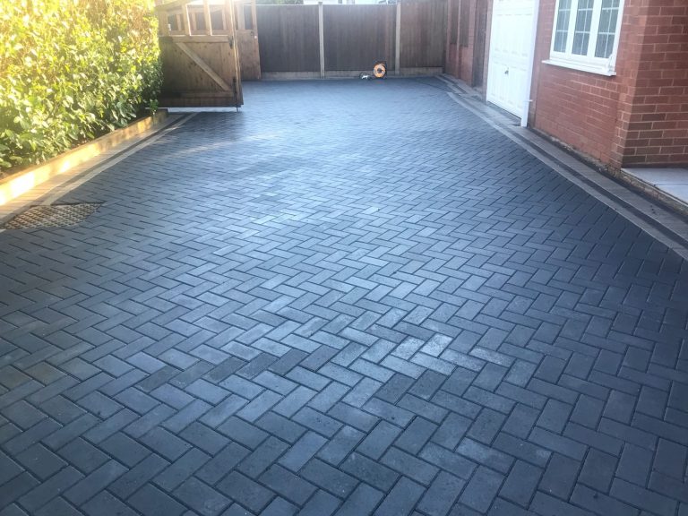 Paved driveway with a smooth, dark surface and surrounding greenery.