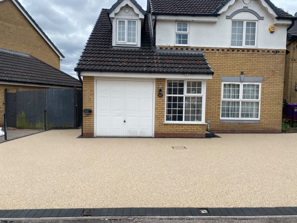 Resin Bound A brick house with a garage and a light-coloured gravel driveway.