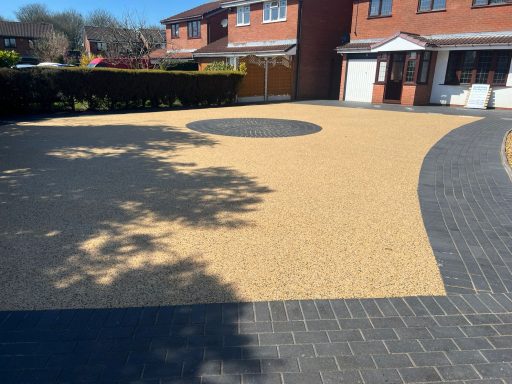 Driveway with a circular area, featuring contrasting yellow gravel and dark paving.