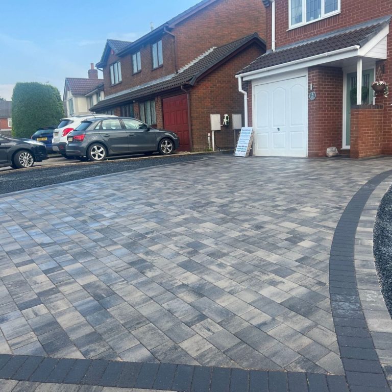 A gravel driveway with red markings and a house with a garage door in the background.
