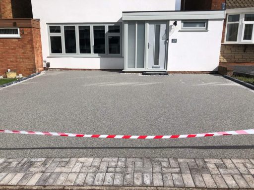 A newly laid gravel driveway in front of a modern home, with a cordon barrier in place.