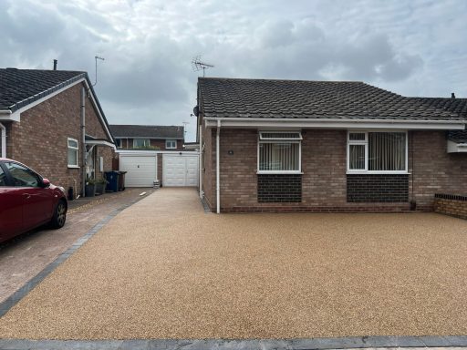 A semi-detached house with a gravel driveway and cloudy sky.