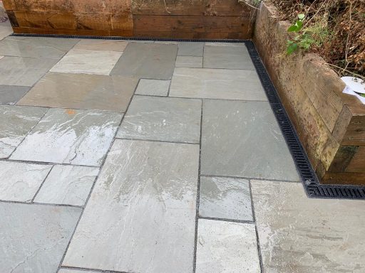 Paved patio area featuring grey stone slabs with some water pooling.