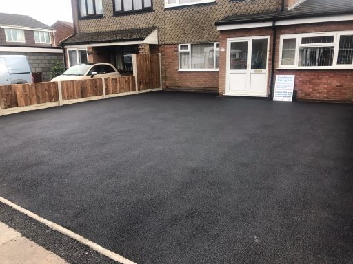 Newly paved driveway with a sign near the entrance of a house.