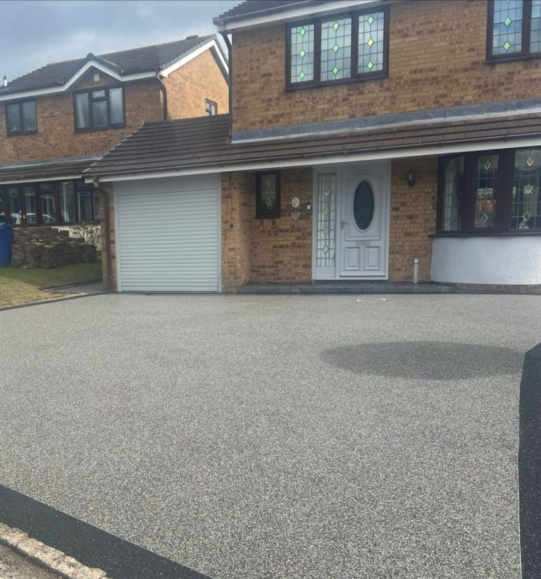 A brick house with a white front door and a grey driveway.