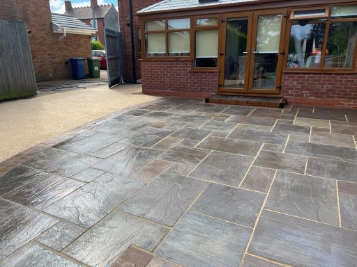 Paved area with stone slabs leading to a house and garden.