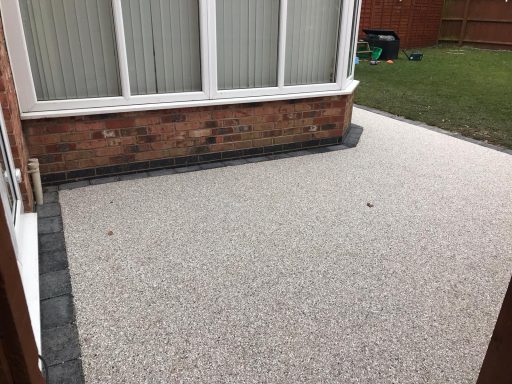 A patio area with a light gravel surface and bordered by dark stone.