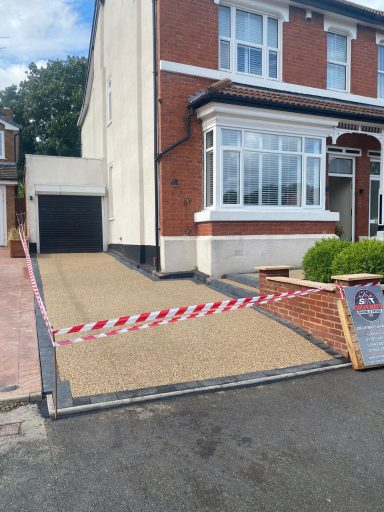 A newly gravelled driveway with a warning sign and red and white tape.