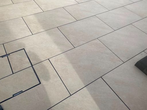 Light-coloured tiled floor with visible grout lines and a shadow in the foreground.