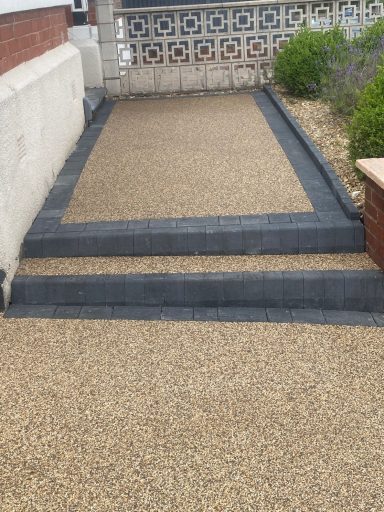 A pathway with concrete borders and gravel surface leading to steps.